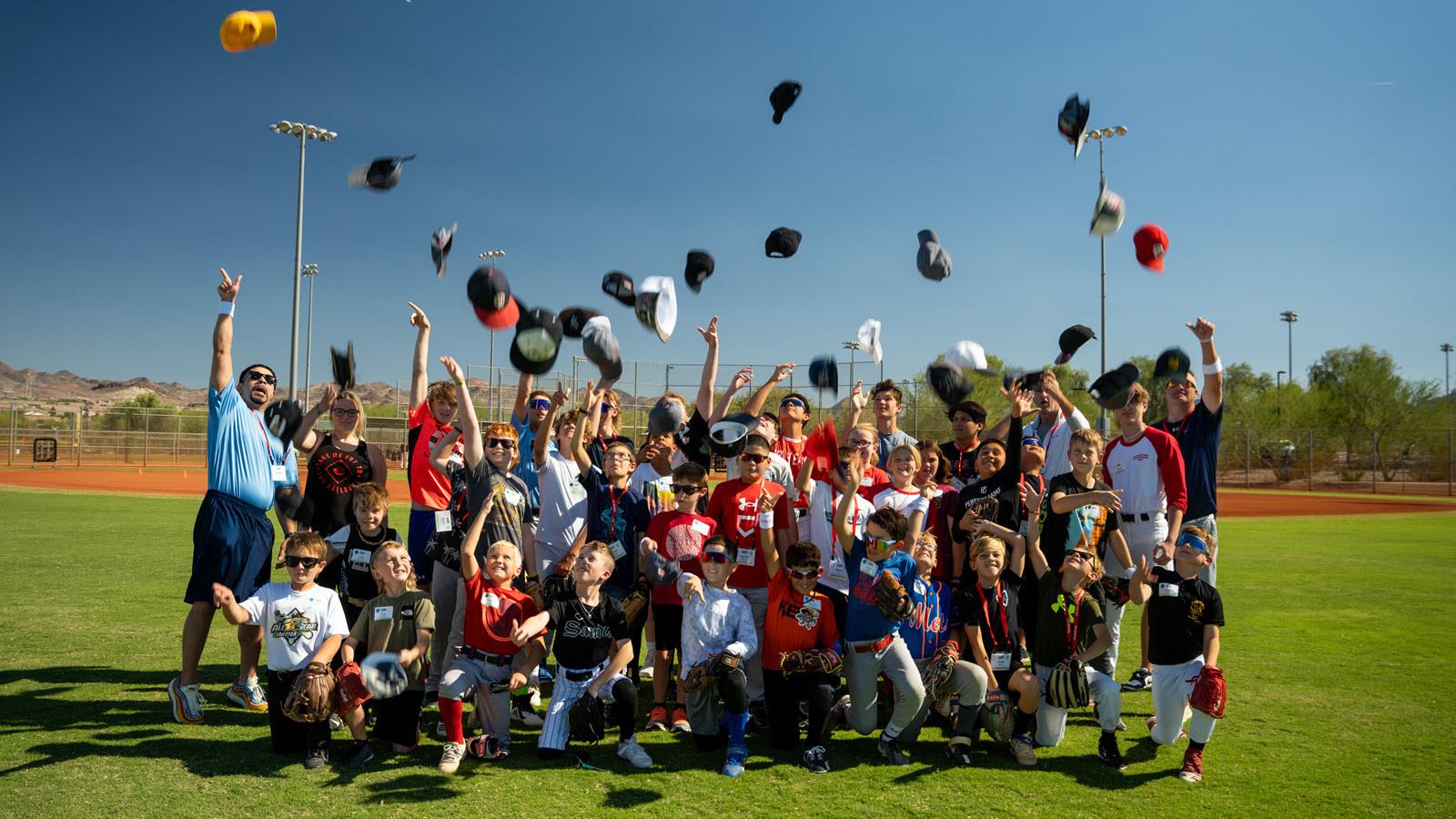 Baseball participants and coaches throw their caps in the air.