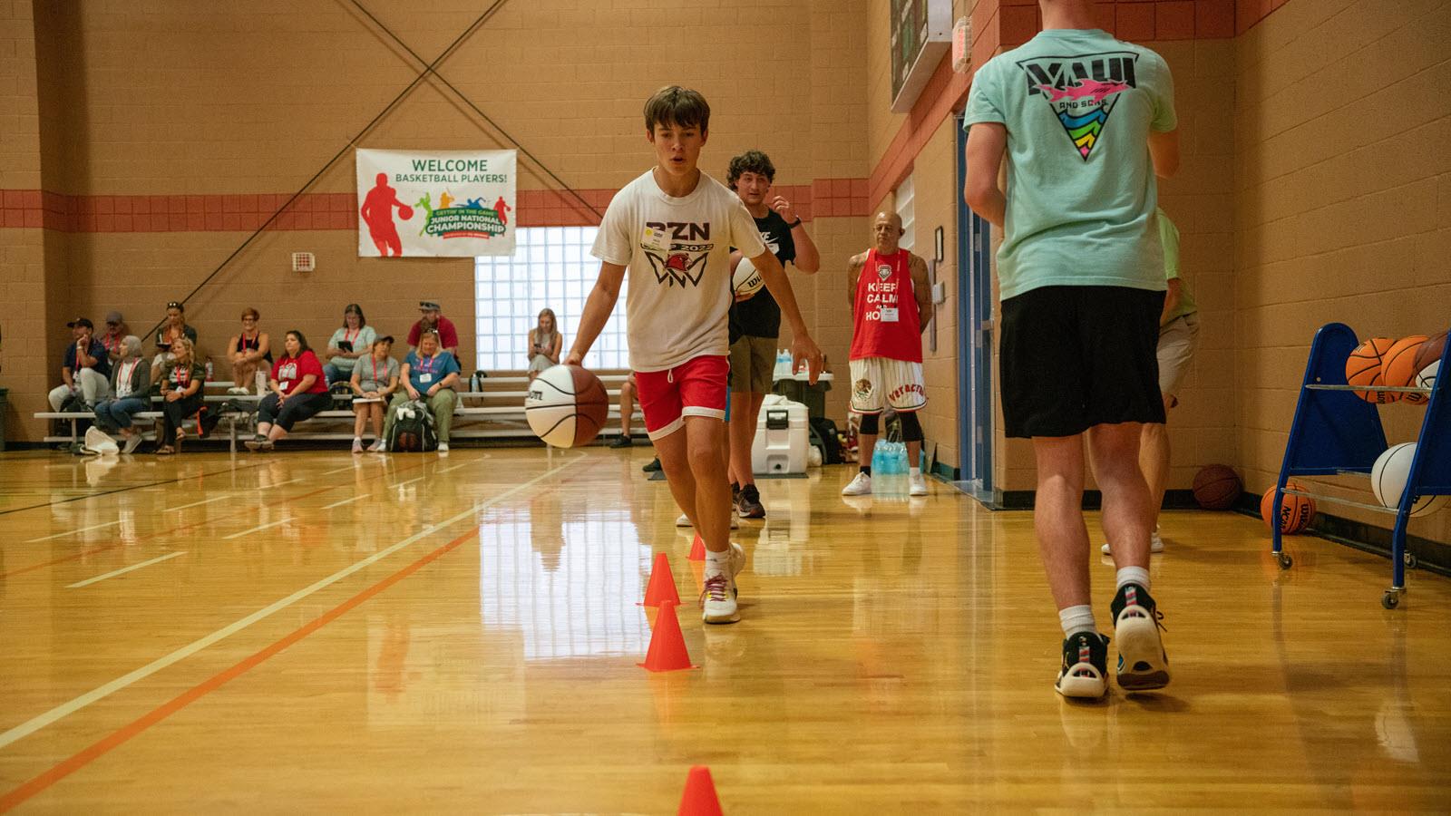 Young basketball player dribbles around a cone.