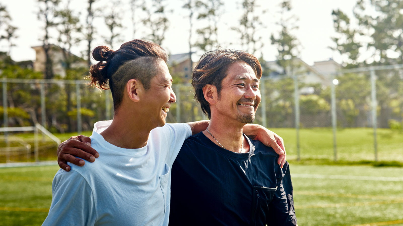 Friends on the soccer field arms around each other's shoulders