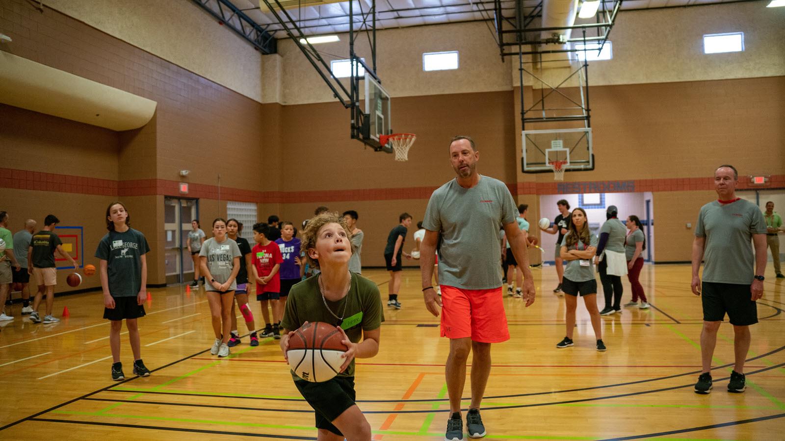 CSL Behring's Bob Lojewski coaches at a youth basketball clinic. A player prepares to shoot.