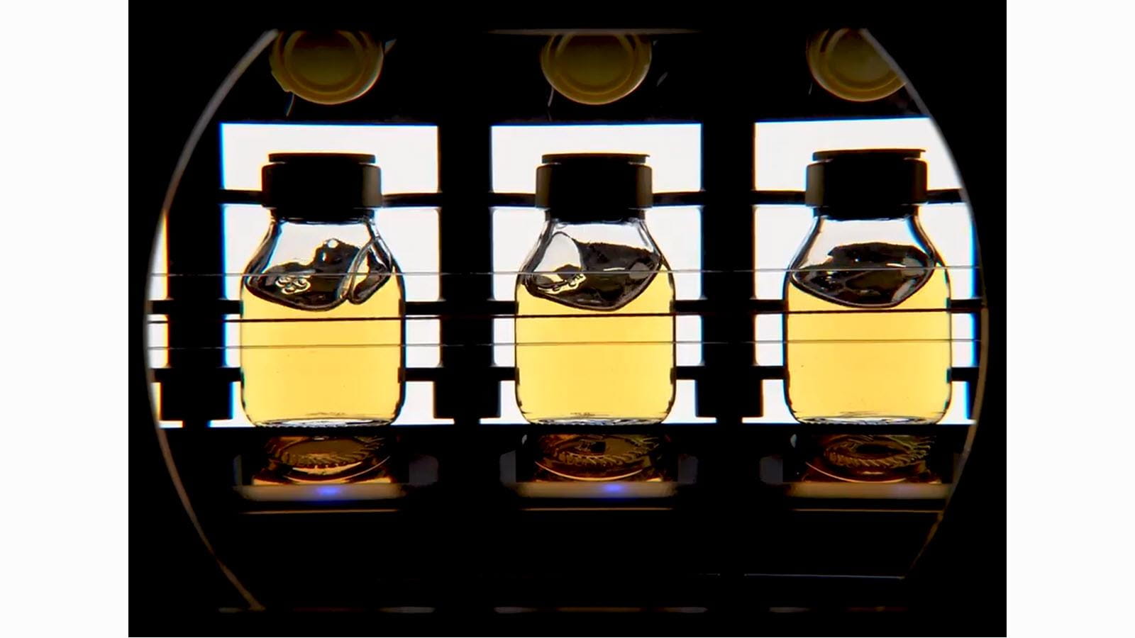 Light shining through three vials of yellow-colored solution