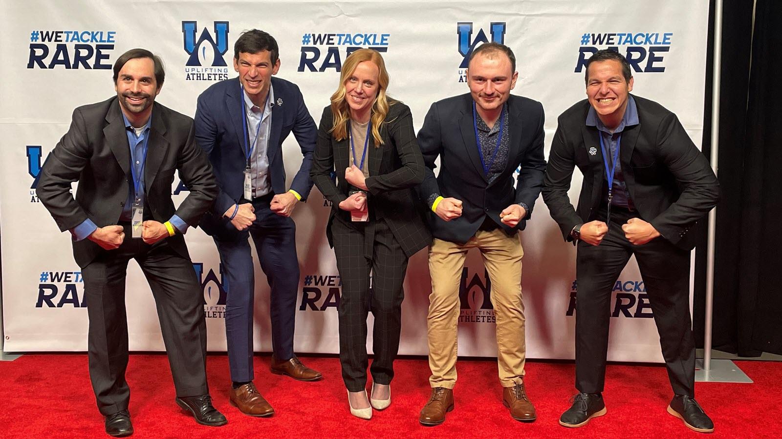 Dr. David Fajgenbaum, researcher Melanie Mau and colleagues strike a fierce pose at the 2023 Uplifting Athletes Young Investigator Draft.