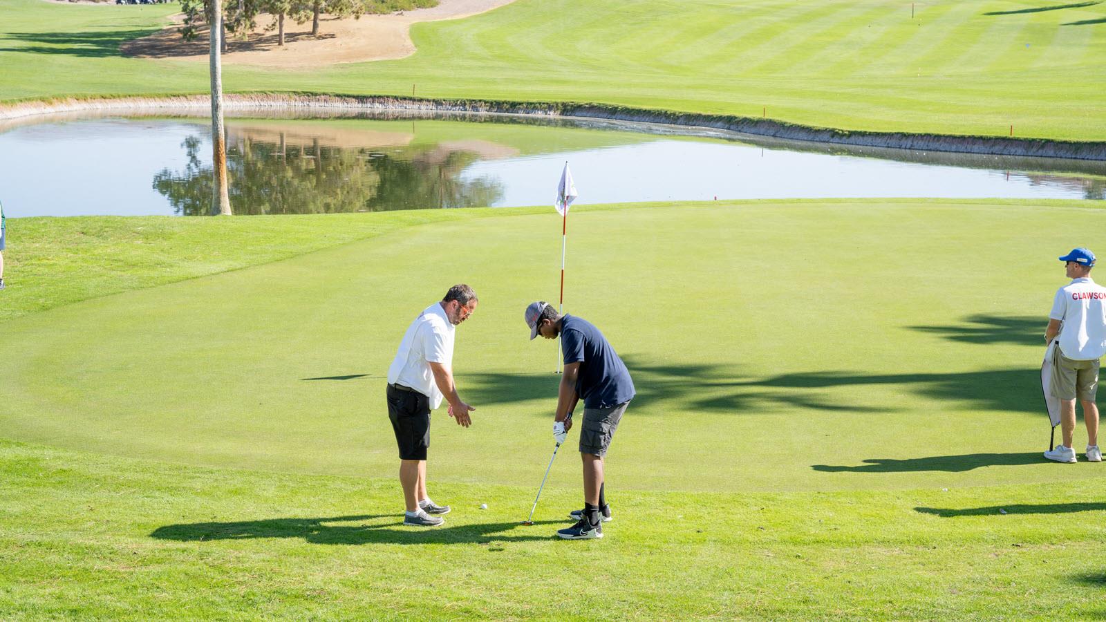 Young golfer gets some guidance on the putt. 