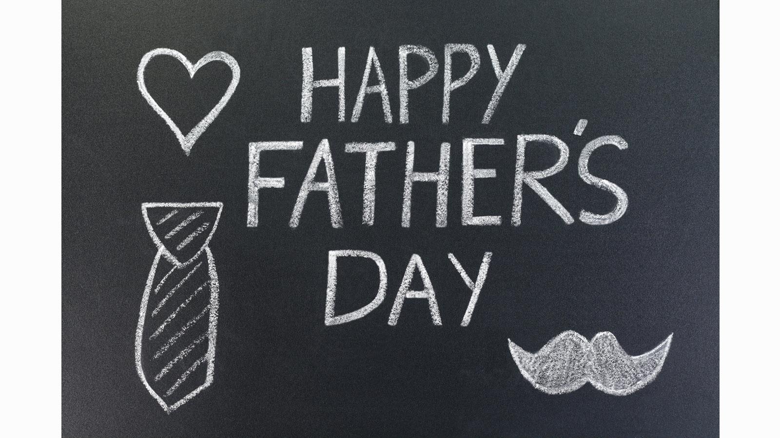 Happy Father's Day written on a chalkboard with drawings of a heart, tie and mustache