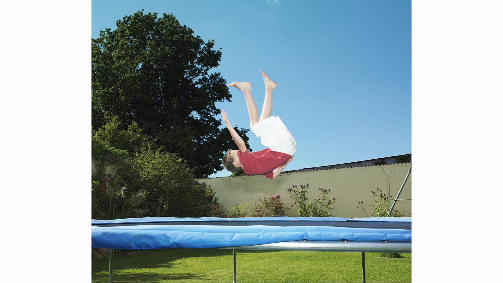 Child flps on an outdoor trampoline