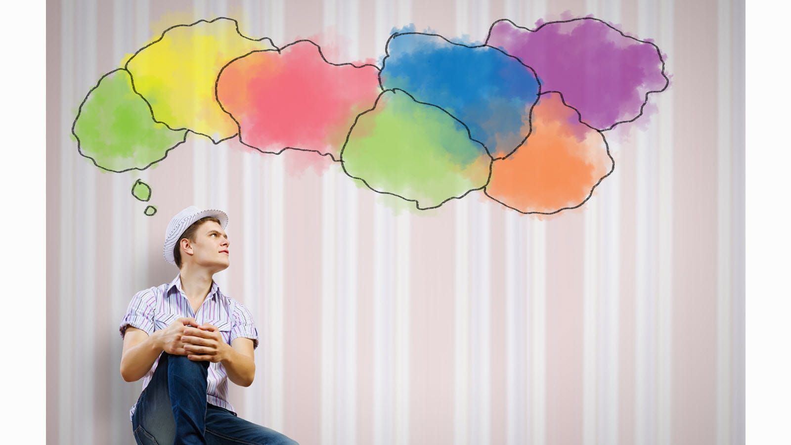 Young man thinks up a multicolored cloud bubble.