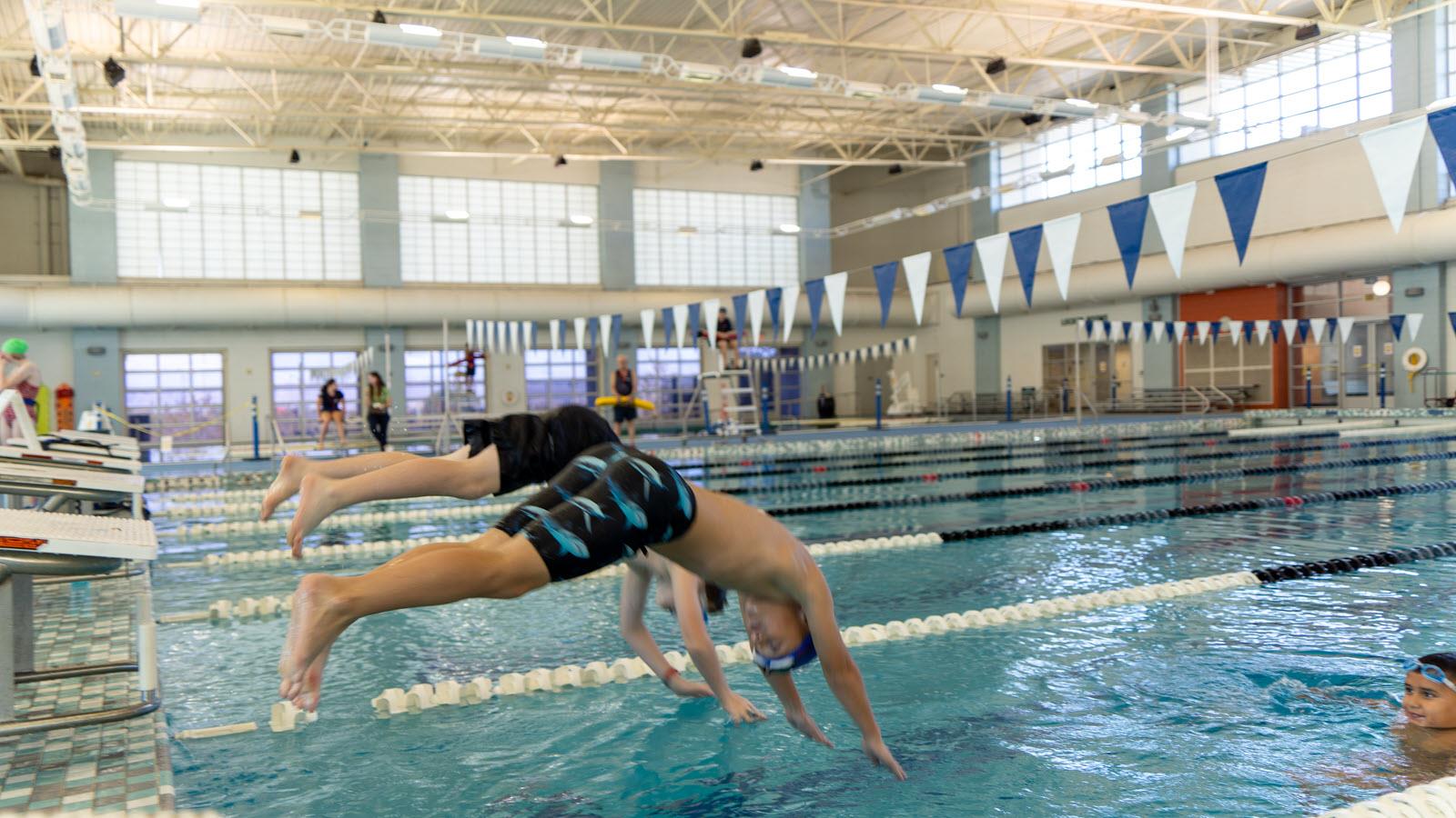 Swimmers dive in.