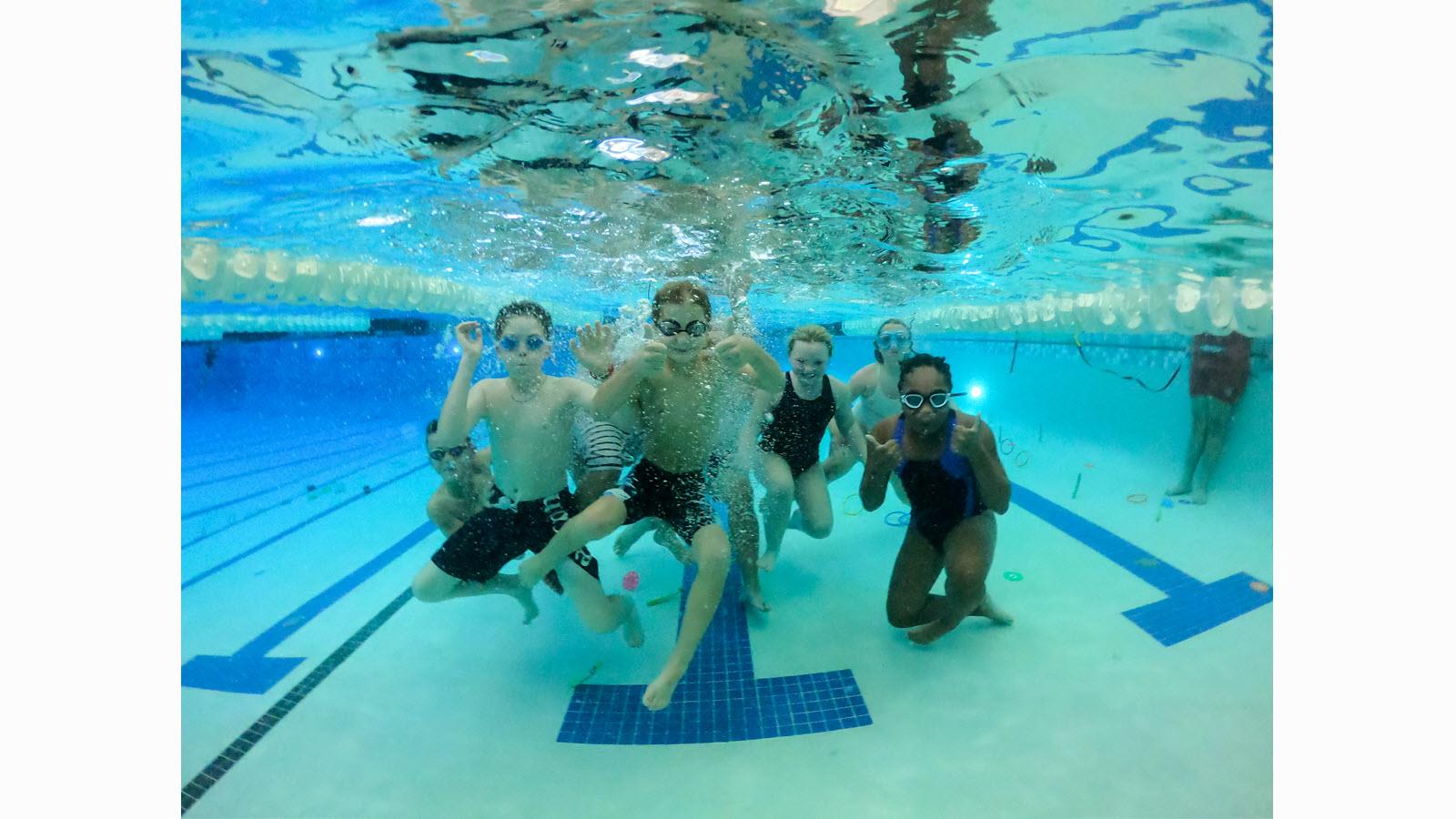 Swimming participants pose underwater.