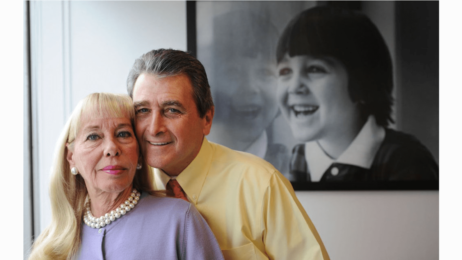 Vicki and Fred Modell in front of a photograph of their son Jeffrey