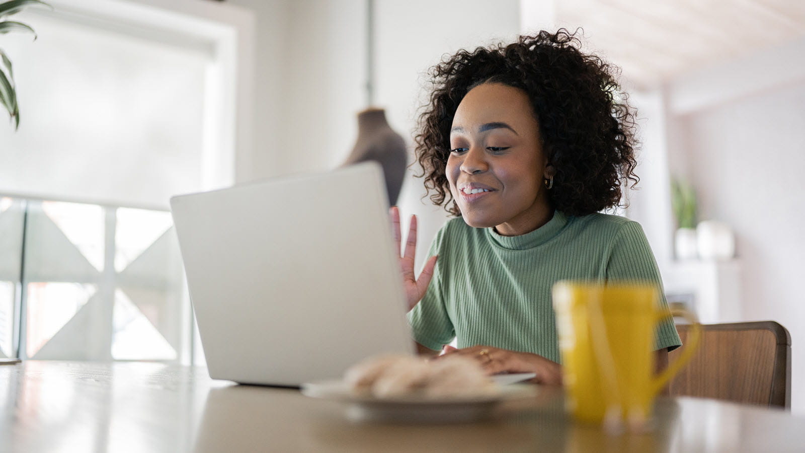 Woman works at home on a laptop at her kitchen table