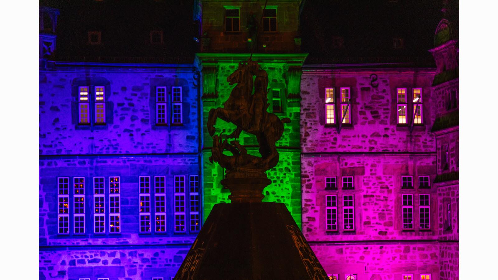 A rooftop finial against the illuminated Town Hall in Marburg, Germany, on Rare Disease Day.