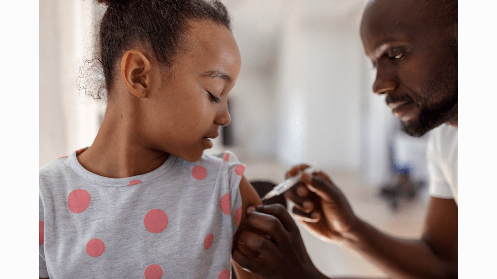 Girl receives a vaccination in her upper arm.