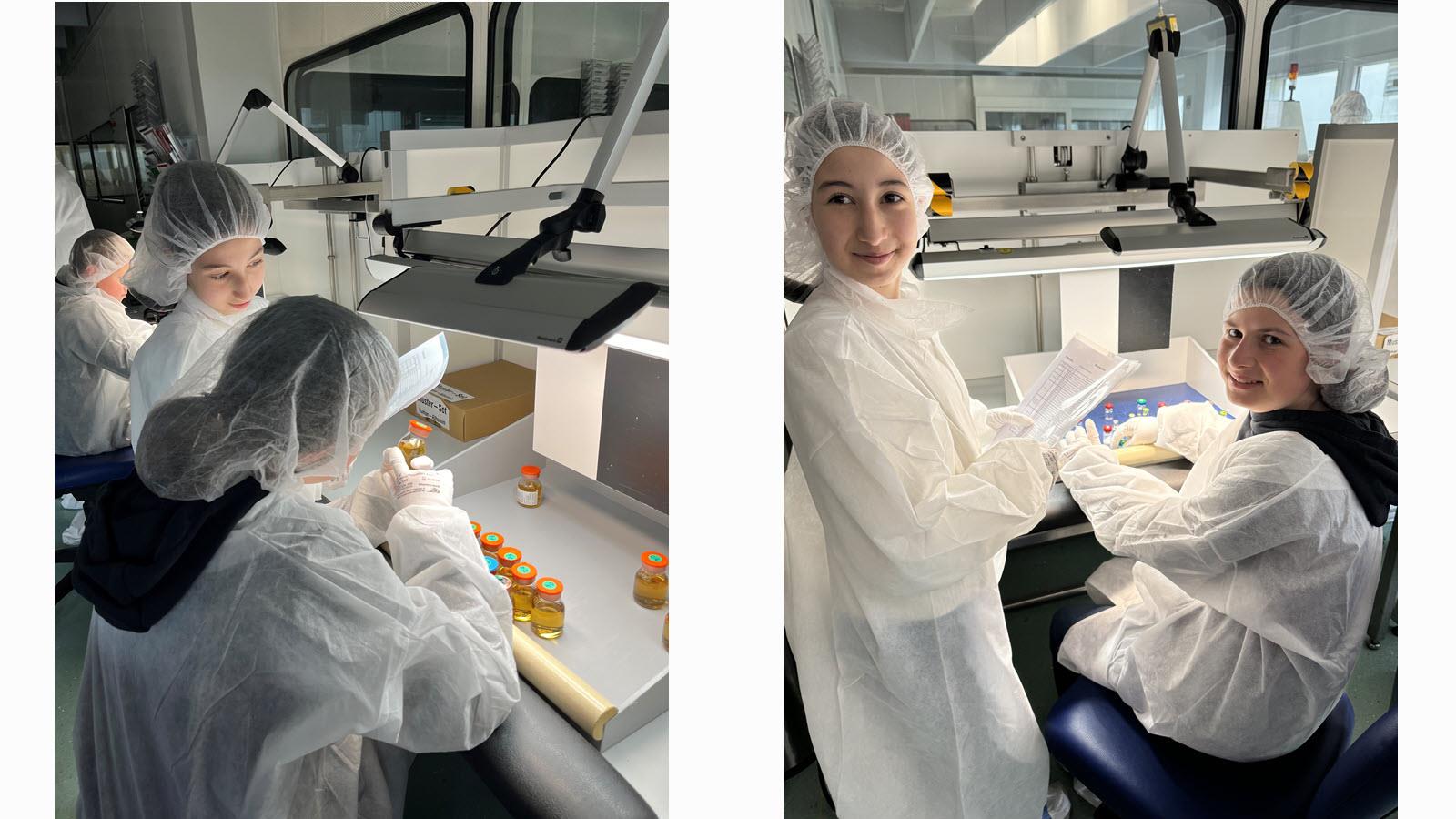 Two girls in protective lab gear inspect vials during a visit to CSL in Marburg, Germany