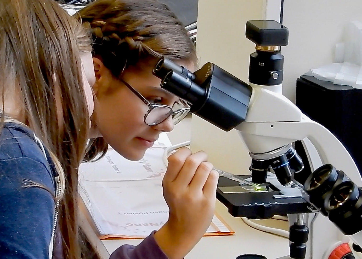 Student leans in while using a microscope
