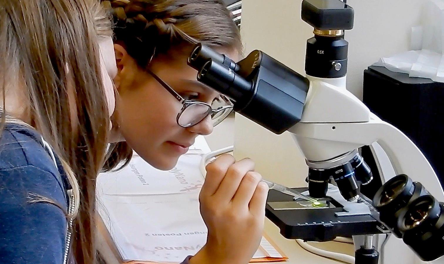Student leans in while using a microscope