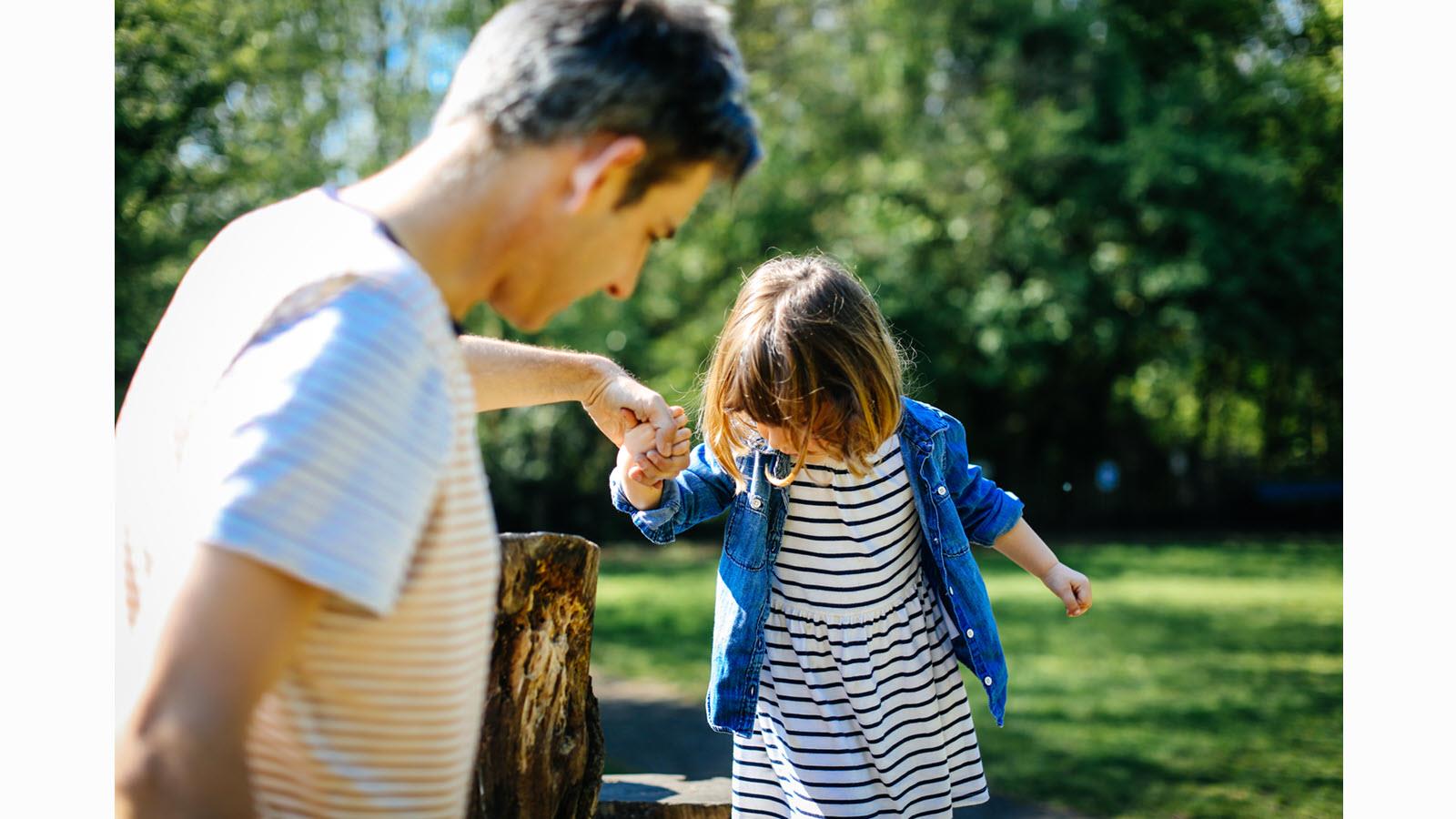 Father holds a young child's hand