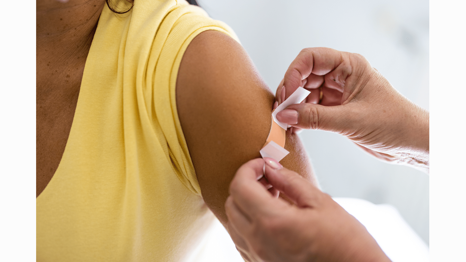 Woman receives a bandage on her upper arm after a vaccine.