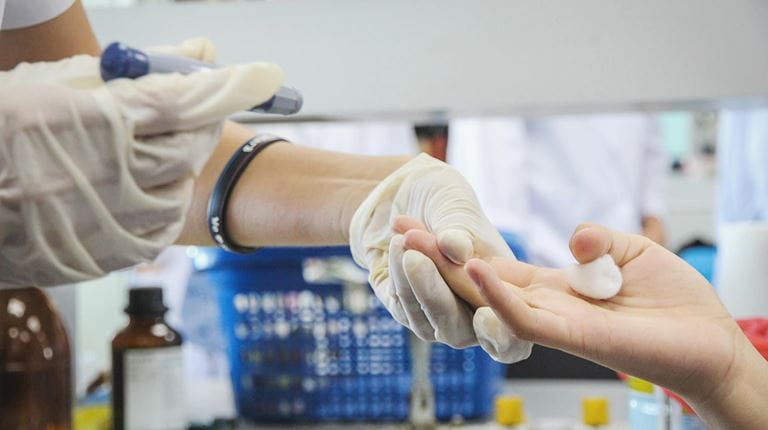 Health care worker takes a patient's hand during a blood test