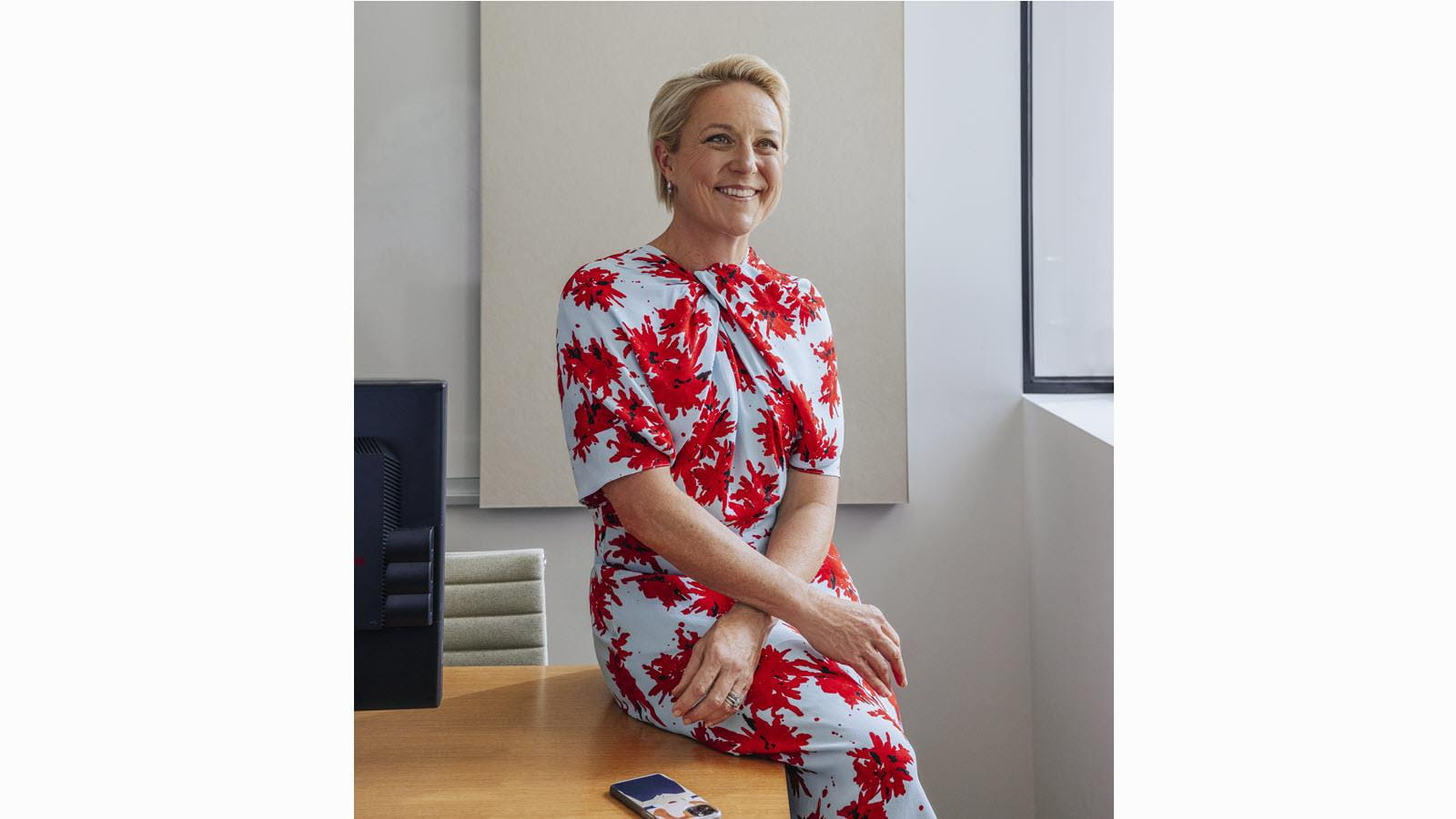 CSL's Bev Menner seated in a floral dress with arms crossed at wrists